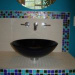 A black bowl sink sitting on top of a white counter.