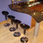 A group of four black stools in front of a bar.