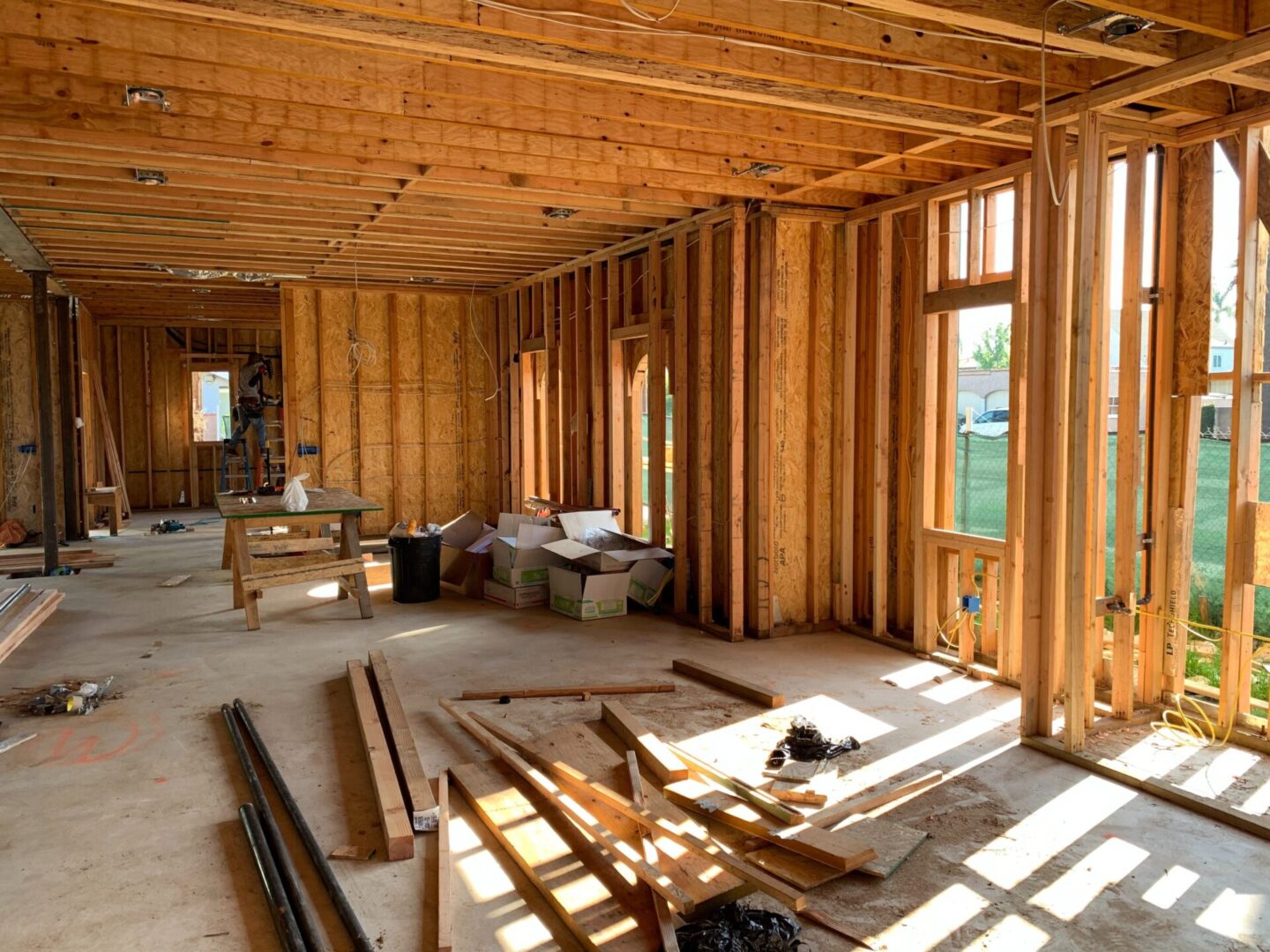Interior framework of a house under construction with exposed wooden studs and scattered building materials.