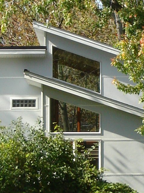 A white house with two windows and trees