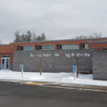 Modern building with a sign reading &quot;seneca nation housing authority&quot; set against a snowy landscape.