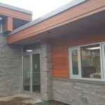 Modern commercial building entrance with stone cladding and wooden accents.
